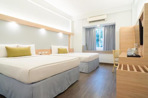 a hotel room with two beds and a desk at Microtel by Wyndham Batangas in Santo Tomas