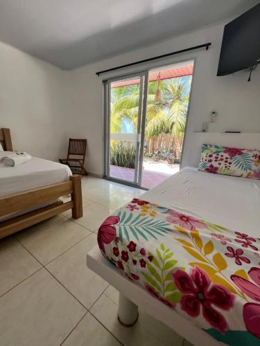 a bedroom with two beds and a large window at Hotel Heliopolis in Coveñas