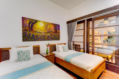 two beds in a room with a painting on the wall at Olala Suite Canggu Guesthouse in Canggu