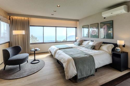 a bedroom with a large bed and a chair at KomoreNest伊豆熱川 in Higashiizu
