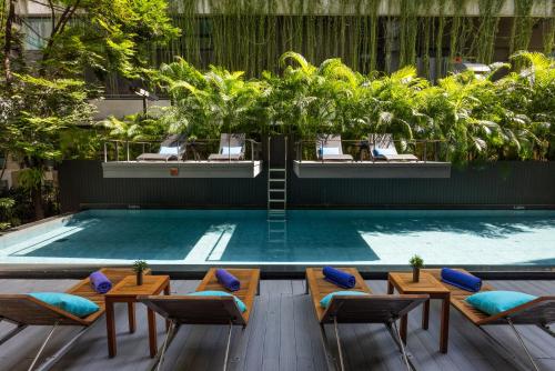 a swimming pool with chairs and a table and a swimming pool at LiT BANGKOK Residence in Bangkok