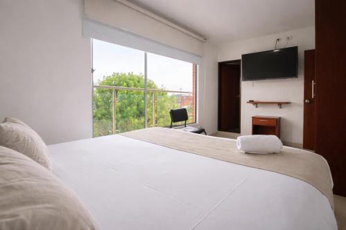 a bedroom with a large bed and a large window at Hotel Dorado Gold in Bogotá