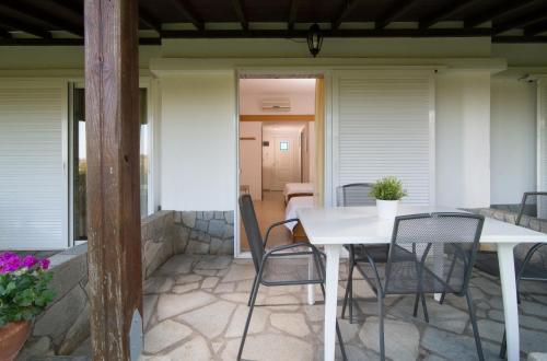 a patio with a white table and chairs on a house at Linaraki Studios & Apartments in Sykia Chalkidikis