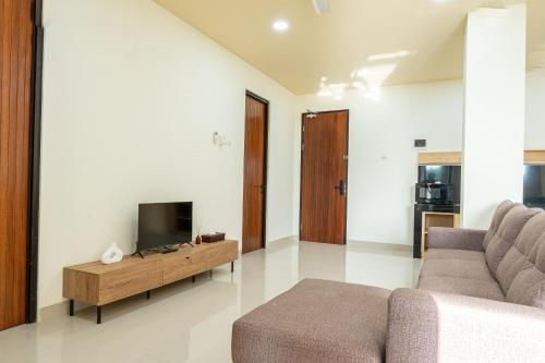 a living room with a couch and a tv at Green Hill Service Apartment in Labuan Bajo