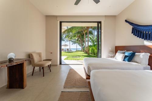 two beds in a room with a view of the ocean at EEB TI KAAN TULUM - Luxury Oceanfront Residences in Tulum