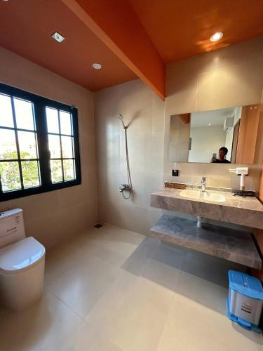 a bathroom with a toilet and a sink and a mirror at ACIS SmartHome NovaWorld in Bình Tú