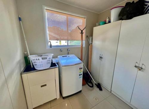 a small kitchen with a refrigerator and a window at Barefoot and Beach Bound by Book Jervis Bay in Vincentia