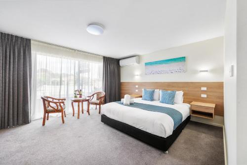 a hotel room with a bed and a table and chairs at Rainbow Motel Queanbeyan in Queanbeyan