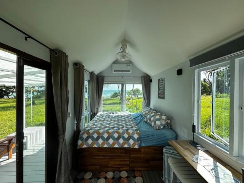 a bedroom with a bed in a room with windows at Beachfront Tiny House - Eden Pod with FREE Rowboat in Nathon Bay