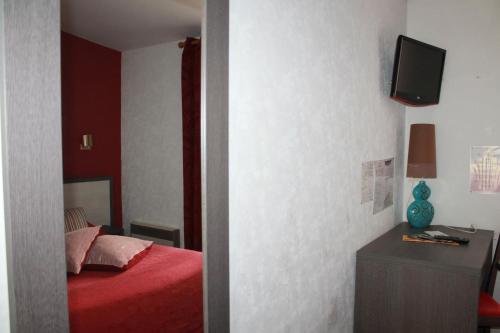a bedroom with a red bed and a tv on the wall at Don Quichotte in Vallet