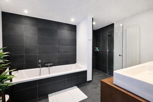 a bathroom with a bath tub and a sink at Luxury Loft Duplex Penthouse Of 190m2 & Free Parking ! in Brussels