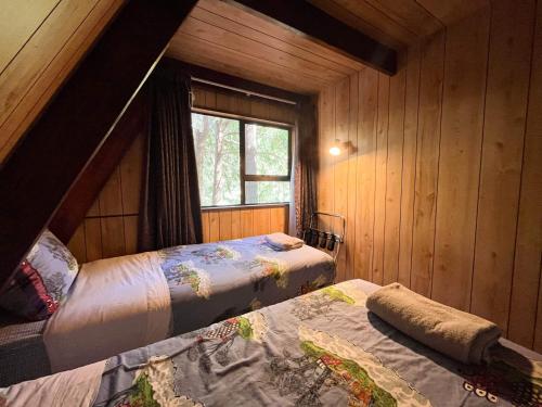 a bedroom with two beds in a wooden cabin at Danseys Pass Holiday Park in Oamaru