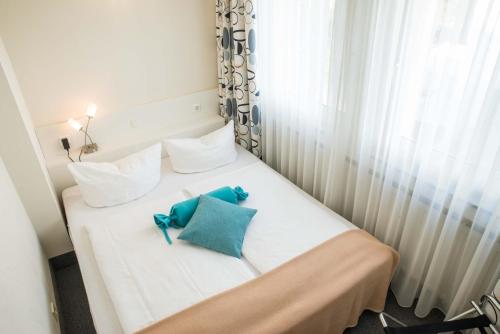 a white bed with two blue pillows on it at ateckhotel Kirchheim/Teck in Kirchheim unter Teck