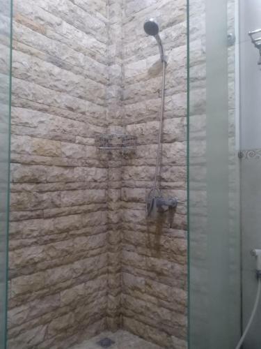 a shower in a bathroom with a stone wall at De Gadri Ndalem Yogyakarta in Bantul