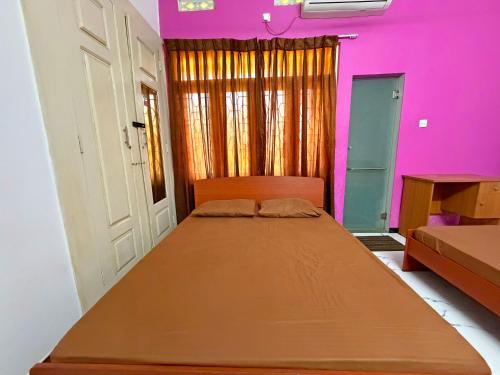 a bedroom with a large bed with pink walls at R&B Guest House in Jaffna