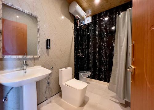a bathroom with a sink and a toilet and a shower at The host in Kanatal