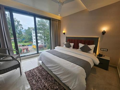 a bedroom with a large bed and a large window at Nirvana Bliss By Cosy Homes, Malsi in Dehradun