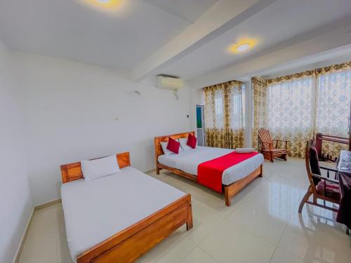 a bedroom with two beds and a table and chairs at Grand View Hotel Kandy in Kundasale