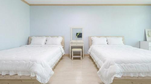 two white beds in a room with a mirror at Goseong Gamnamu Pension in Goseong