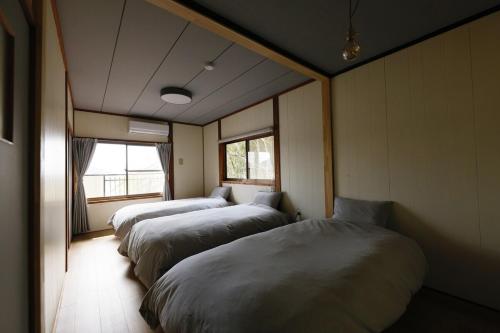 a row of three beds in a room at CLIP INN by RITO 坂の上の一棟貸し in Tsushima