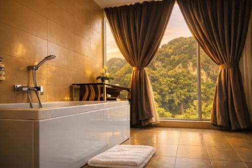a bathroom with a tub and a large window at Symphony Suites Hotel in Ipoh