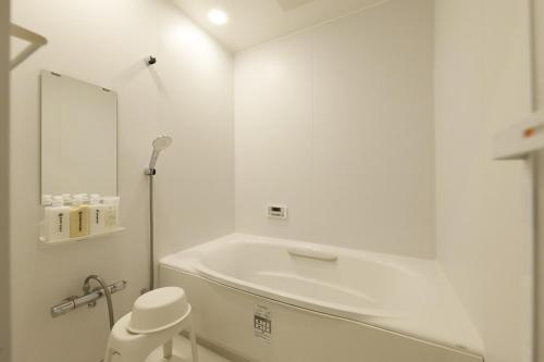 a white bathroom with a tub and a toilet at CLIP INN by RITO 坂の上の一棟貸し in Tsushima