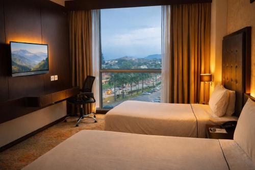 a hotel room with two beds and a large window at Symphony Suites Hotel in Ipoh