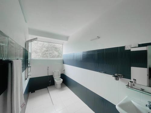 a bathroom with a toilet and a sink and a window at Grand View Hotel Kandy in Kundasale