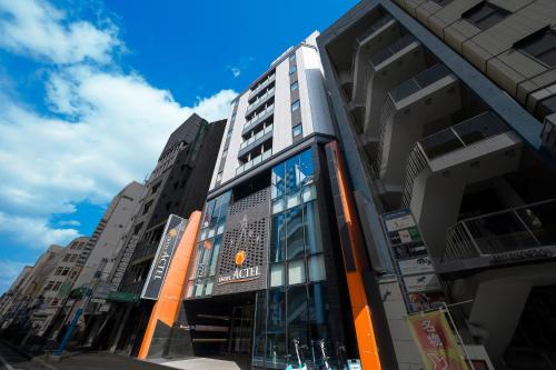 a building on a city street with tall buildings at Hotel Actel Nagoya Nishiki in Nagoya