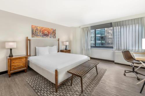a bedroom with a large bed and a desk and chair at The Quincy, an Ascend Collection Hotel in Washington, D.C.