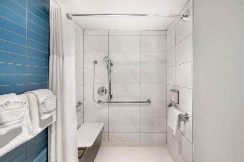 a bathroom with a shower with white tiles at The Quincy, an Ascend Collection Hotel in Washington, D.C.