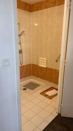 a bathroom with a shower and a tiled floor at Hotel Du Rocher in Le Caylar