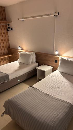 a hotel room with two beds and a table at Hotel Du Rocher in Le Caylar
