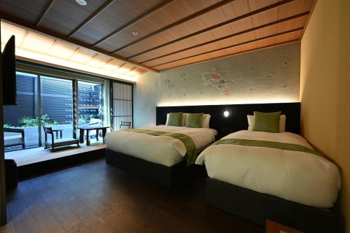 two beds in a room with a table and a window at Kiyomizu Elite Terrace in Kyoto