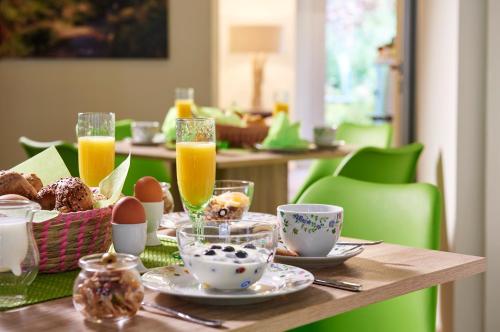a table with a breakfast of eggs and orange juice at Auenwald Hotel und Apartmenthaus in Leipzig