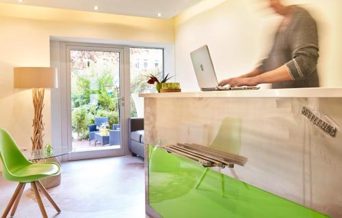 a man standing at a counter with a laptop at Auenwald Hotel und Apartmenthaus in Leipzig