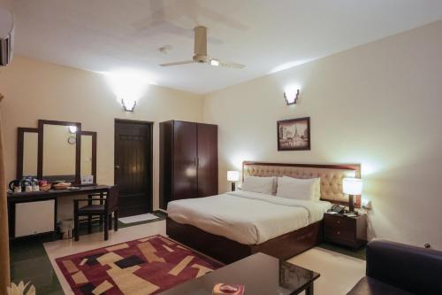 a bedroom with a bed and a table and a couch at Hotel One Bahawalpur in Bahawalpur