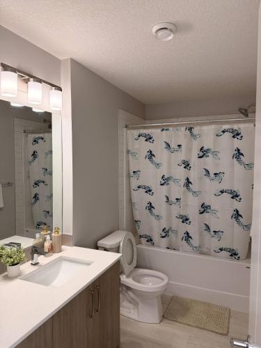 a bathroom with a toilet and a shower curtain with dolphins at Cozy and comfortable in Calgary