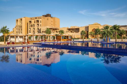 a resort with a pool with palm trees and buildings at InterContinental Durrat Al Riyadh Resort & Spa, an IHG Hotel in Riyadh