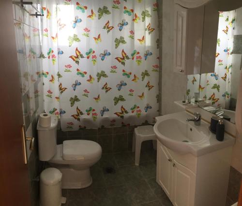 a bathroom with a toilet and a shower curtain with butterflies at Kalloni Royal Resort in Kalloni
