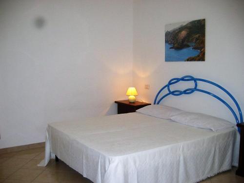a bedroom with a white bed with a lamp on a table at Le Mimose in Cala Liberotto