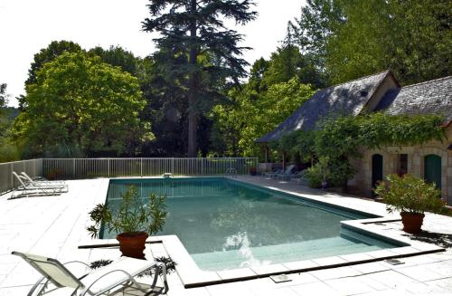 a swimming pool with chairs and a house at Hostellerie de la Commanderie in Condat-sur-Vézère