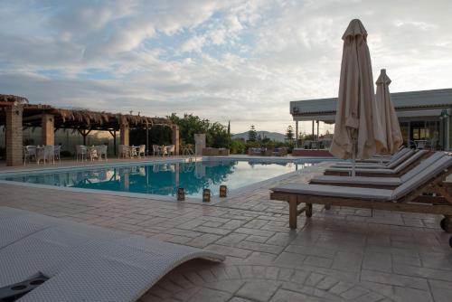 einen Pool mit 2 Liegestühlen und einem Sonnenschirm in der Unterkunft Kalloni Royal Resort in Kalloni