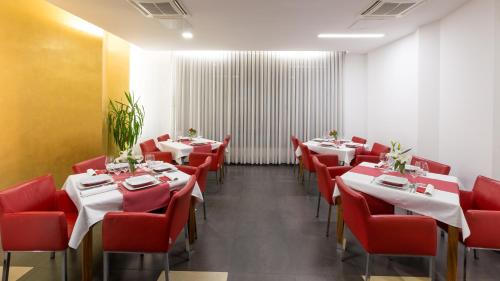 a dining room with red chairs and tables in a restaurant at Dream Hotel in Velika Gorica
