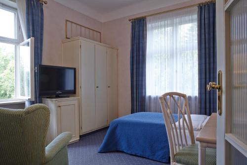 a bedroom with a bed and a tv and a chair at Hotel Bad Schachen in Lindau