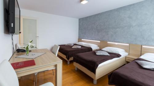 a room with two beds and a desk and a television at Dream Hotel in Velika Gorica