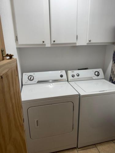 a kitchen with white cabinets and a washer and dryer at Big Bass Bungalow - Quitman Tx in Quitman
