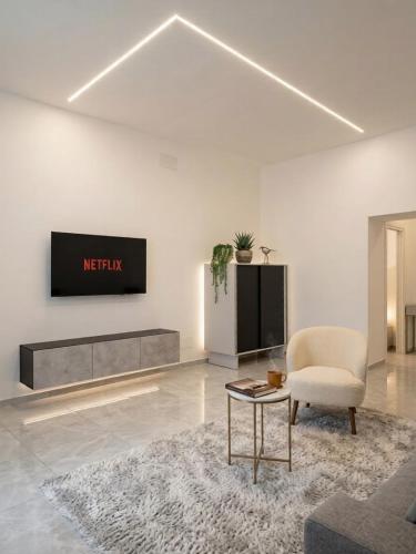 a living room with a tv and a chair and a table at Aura - Luxury Suite in Syracuse