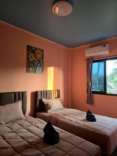 a bedroom with two beds and a window at โรงแรมเลทุ่งแล่น 109 in Ban Phru Ching (1)