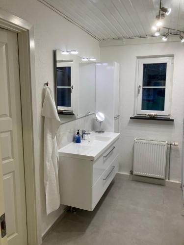 a white bathroom with a sink and a mirror at Hegedal Fjordhouse in Hobro